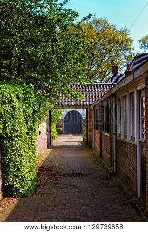 A blue double door at the end of a narrow corridor in a pittoresque residental area in the town of Bussum the Netherlands.
