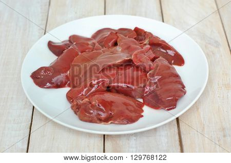 Raw Liver On The White Plate On The Wooden Background
