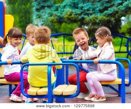 Happy Kids Having Fun On Roundabout At Playground