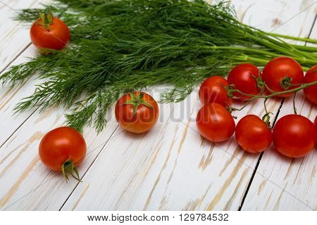 Tomatoes and herbs on white wooden background