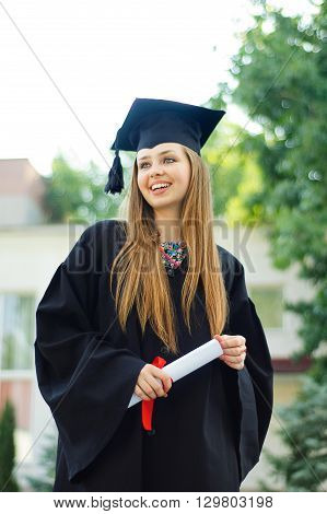 Student enjoys graduation. In her hands the diploma. Girl smiling