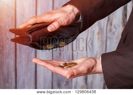 Hands holding coins and wallet. Black wallet and small coins. Not a cent more. The definition of poverty.