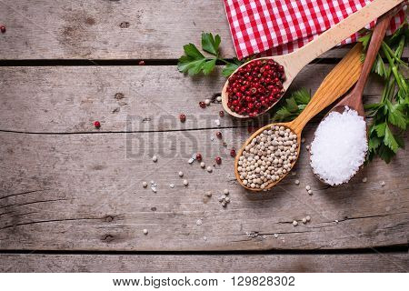 Seasoning for cooking. Red and white pepper and sea salt in wooden spoon on aged wooden background. Food ingredient. Selective focus. Place for text. Flat lay. Top view.