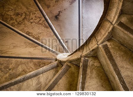 A stone staircase winds its way upwards with a sprial geometric shape in an old building in Sintra Portugal.