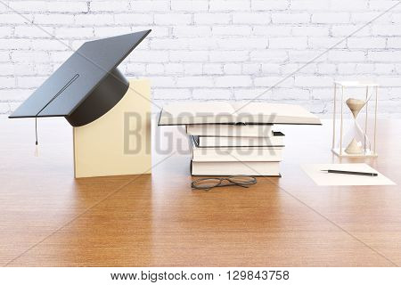 Graduation concept with book graduation cap hourglass and spectacles on wooden desktop with brick wall in the background. 3D Rendering