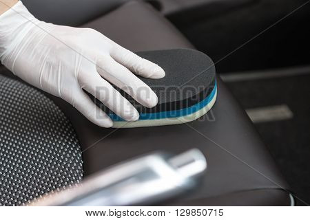 Car detailing series : Closeup of hand cleaning dark leather car seats