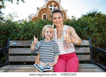 Happy Mother And Child Istening Audioguide And Showing Thumbs Up
