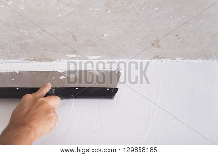 house improvement by worker puts finishing layer of stucco on the wall using a plastering trowel