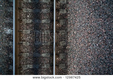 Rails and cross ties of railway among stones at left