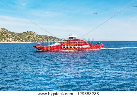 Keramoti, Greece - May 1, 2016: Red ferry boat going to Thassos from Keramoti port, blue sea and sky