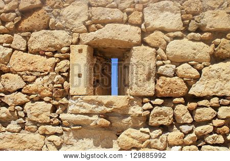 Window in old stone wall ruins of a medieval fortress on Crete Island, Greece