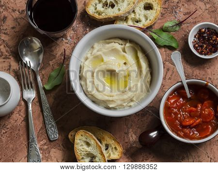 Delicious lunch - bean puree tomato sauce with carrots and onions homemade bread glass of red wine on a stone background. Top view