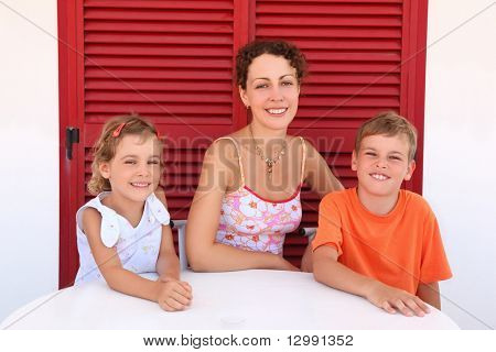 Мать с двух детей сидеть рядом закрытая дверь круглый стол и улыбкой