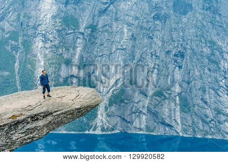 Young Man Standing On Rock In The Mountains Of Norway. Natural Attractions Of Trolltunga - Troll Tongue.