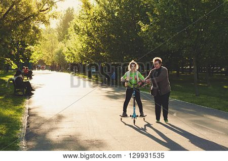 Bucharest, ROMANIA - April 22 2016: People in Izvor Park. Grandmother teaching her neice how to ride a scooter. BUCHAREST -April 22 2016