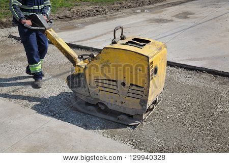 Worker Use Vibratory Plate Compactor At Road Construction Site