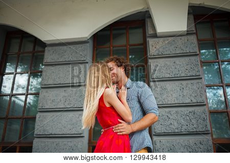 The curly-haired guy with the red-haired girl with freckles on the background of fabulous scenery of city and nature. Lovely couple of lovers on a walk in the city and nature. Tenderness emotion