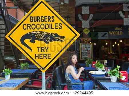 Siem Reap, Cambodia - MAY 04, 2016: An unknown woman in a cafe, which serves burgers from a crocodile. 