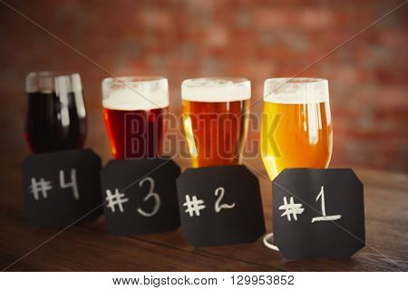 Glasses with different sorts of craft beer and numbering on wooden table. Retro blurred

