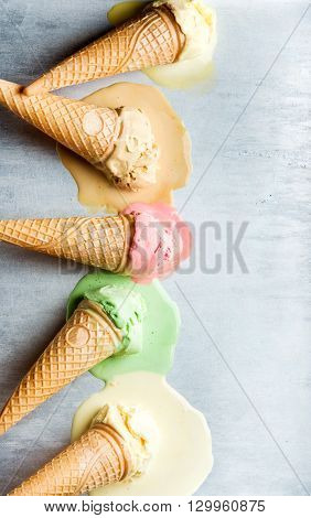 Colorful ice cream cones of different flavors. Melting scoops. Top view, copy space, steel metal background