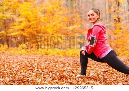 Stretching and exercising. Young sporty fit girl doing sports outdoor. Positive woman spending time on fresh air in autumnal forest.