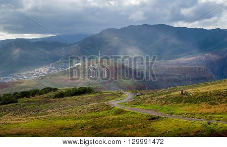 Serpentine road in the beautiful landscape of Madeira island. Fields and hills, wind generators and mountain range view. Canical, Madeira, Portugal.