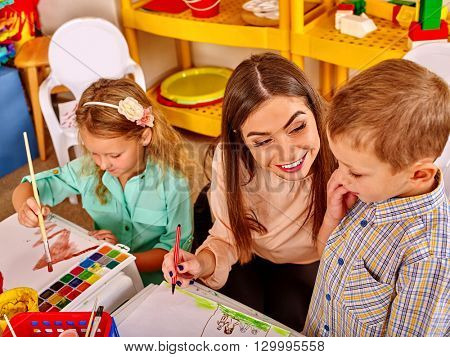 Children with teacher woman painting on paper at table  in  kindergarten . Learning children in start school.