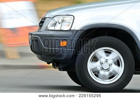 Wheel Of Automobile In Motion.  Car Moving, But In Focus, Street And Whell Blurred