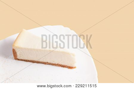 Classic Cheesecake On A White Plate Isolated On Beige