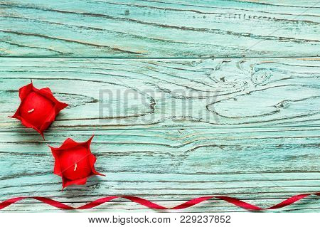 Two Candles Of Red Color On A Background Of Turquoise Wood. The Concept Of Valentine's Day.