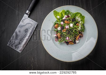 Plate With Wegan Arugula Walnuts Salad And Knife Over Black Rustic Wood