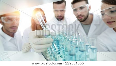 background image is a group of microbiologists studying the liqu