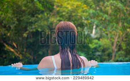 Woman In Blue Water. Loose Hair Girl In Open Swimming Pool. Tropical Jungle Resort. Summer Vacation 