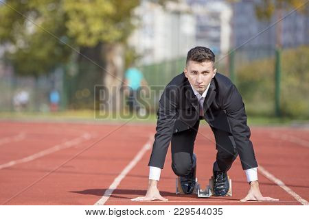 Business Man In Suit Starting And Preparing To Run On The Competition Running Performance Track.