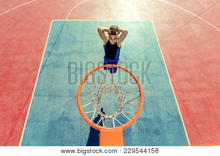 High Angle View Of Basketball Player Dunking Basketball In Hoop.