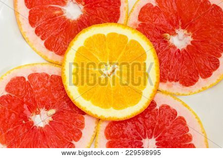 Top View Of A Fragment Of Several Round Slices Of The Ripe Red Grapefruit And Orange With Their Peel