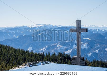 Panoramic Snowy Landscape Scenic View From Summit Of Mountain Rennfeld With Cross And Distant Mounta
