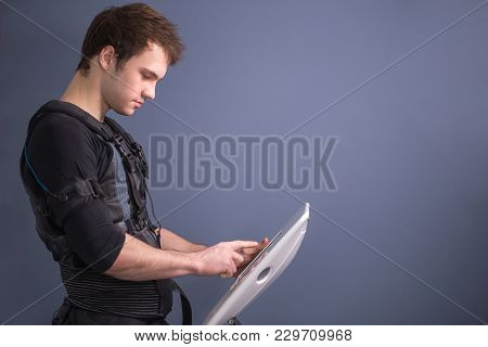 Male Athlete Pushing On Screen On Ems Machine Regulating Intensity