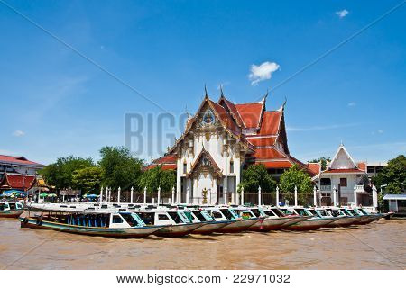 Templo de arte tailandés y longtail boat en riverside