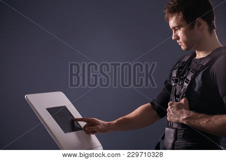 Male Athlete Select Intensity Of Ems Electro Muscular Stimulation Machine