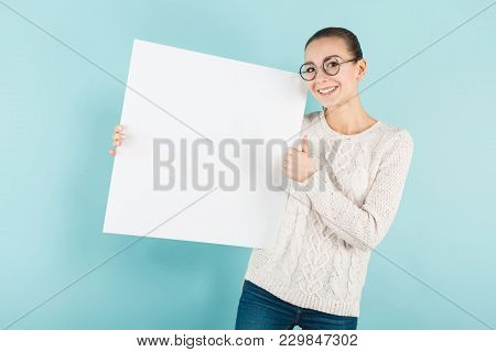 Portrait Of Attractive Happy Woman In Sweater And Round Glasses Isolated On Blue Background Holding 