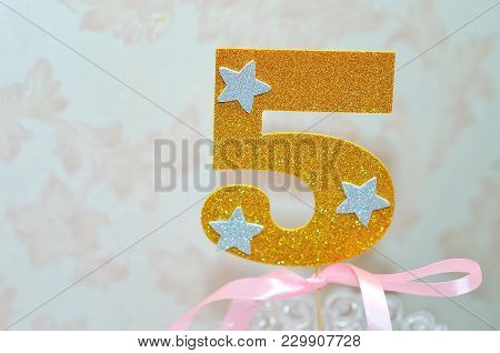 Gold Number 5 Celebration Candle Against Blurred Light Background