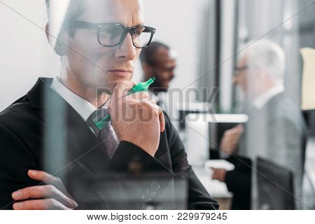 Selective Focus Of Focused Businessman Looking At Sticky Notes While Multicultural Colleagues Having