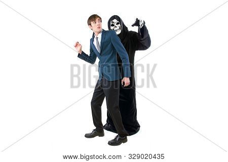 Man In A Halloween Grim Reaper Ghost Costume Chasing, Mocking And Making Fun Of Scared Businessman R