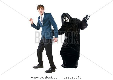 Man In A Halloween Grim Reaper Ghost Costume Chasing, Mocking And Making Fun Of Scared Businessman R