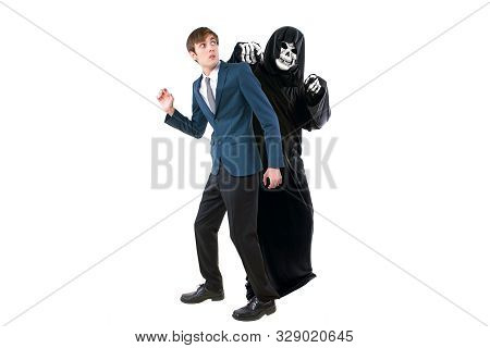 Man In A Halloween Grim Reaper Ghost Costume Chasing, Mocking And Making Fun Of Scared Businessman R