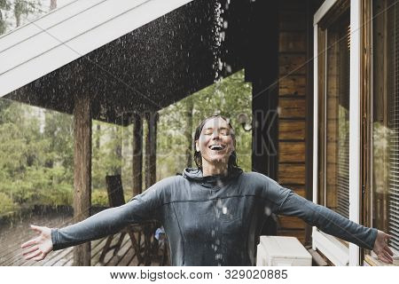 Happy Woman Spread Her Arms To The Side And Enjoying The Warm Rain. She Is Throwing Her Head Back, S
