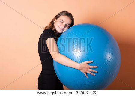 Girl On A Gym Ball, On A Light Orange Background.