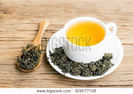 Dry Gynostemma Pentaphyllum Leaf With Brewed Tea In A White Cup On The Wood Floor