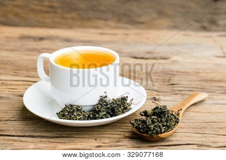 Dry Gynostemma Pentaphyllum Leaf With Brewed Tea In A White Cup On The Wood Floor